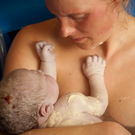 Mutter kurz nach der Geburt mit Neugeborenem Baby auf dem Arm